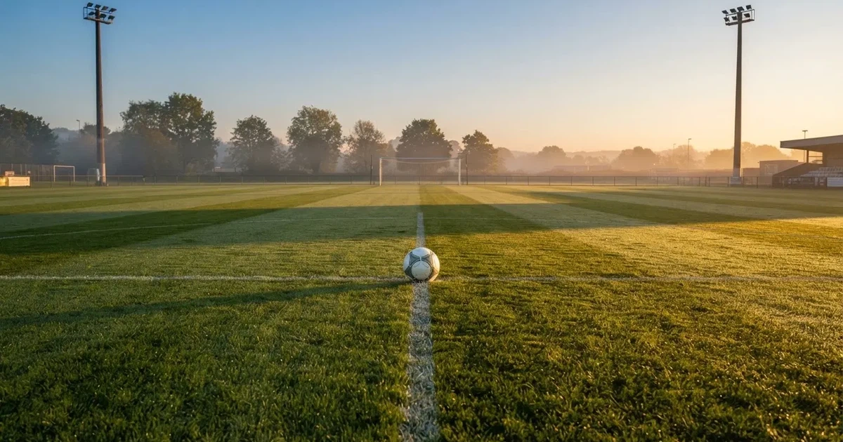Un balón en el punto central de un campo de césped a la luz de la mañana