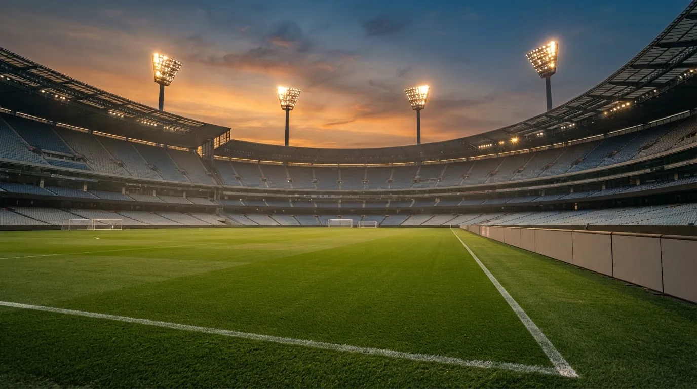 Un estadio de fútbol vacío con torres de iluminación al atardecer