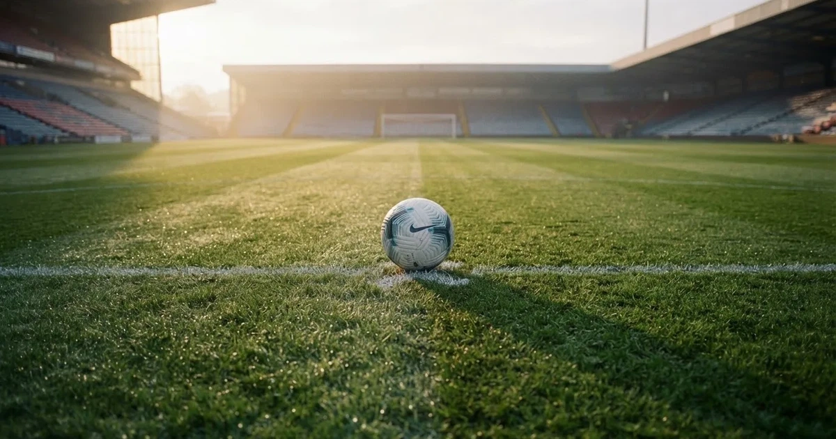 Un balón en el punto central de un campo de césped a la luz de la mañana