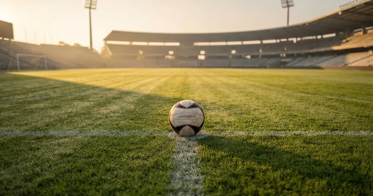 Un balón en el punto central de un campo de césped a la luz de la mañana