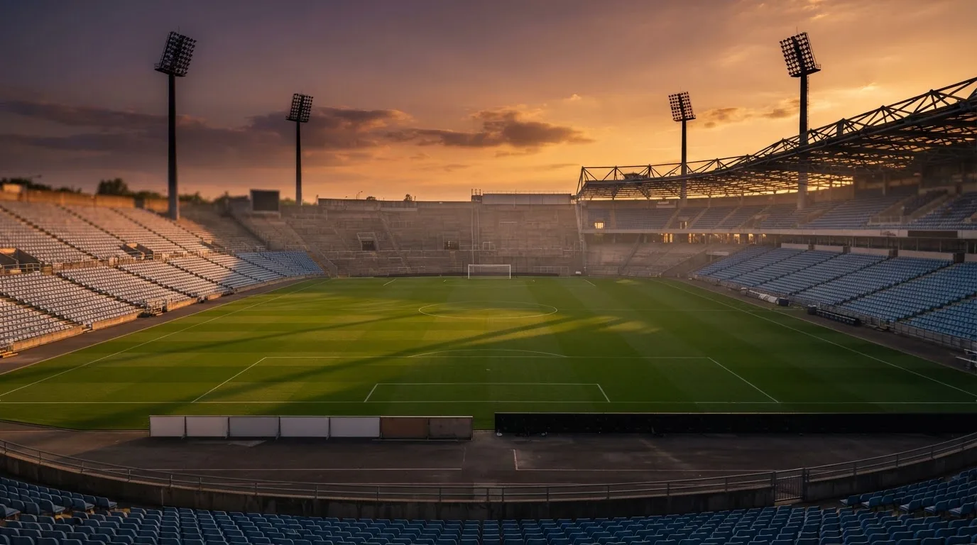 Un estadio de fútbol vacío con torres de iluminación al atardecer