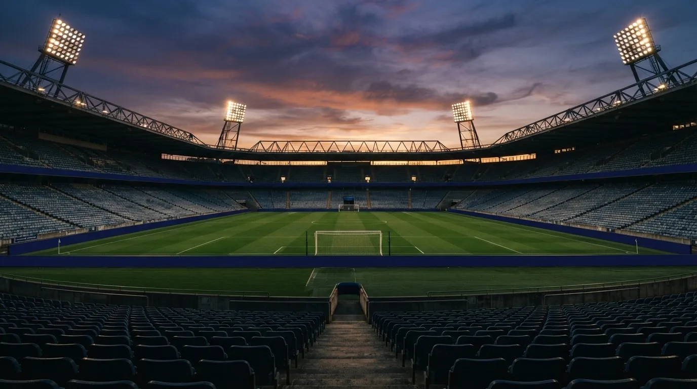 Un estadio de fútbol vacío con torres de iluminación al atardecer