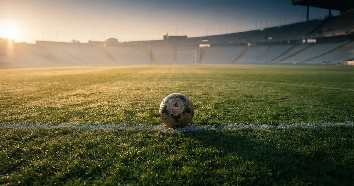 Un balón en el punto central de un campo de césped a la luz de la mañana