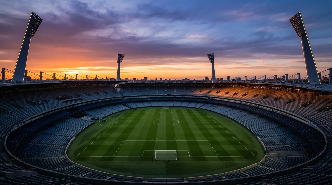 Un estadio de fútbol vacío con torres de iluminación al atardecer
